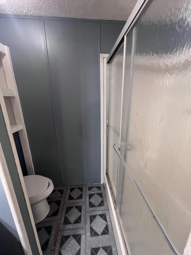 full bath featuring a stall shower, toilet, and tile patterned floors