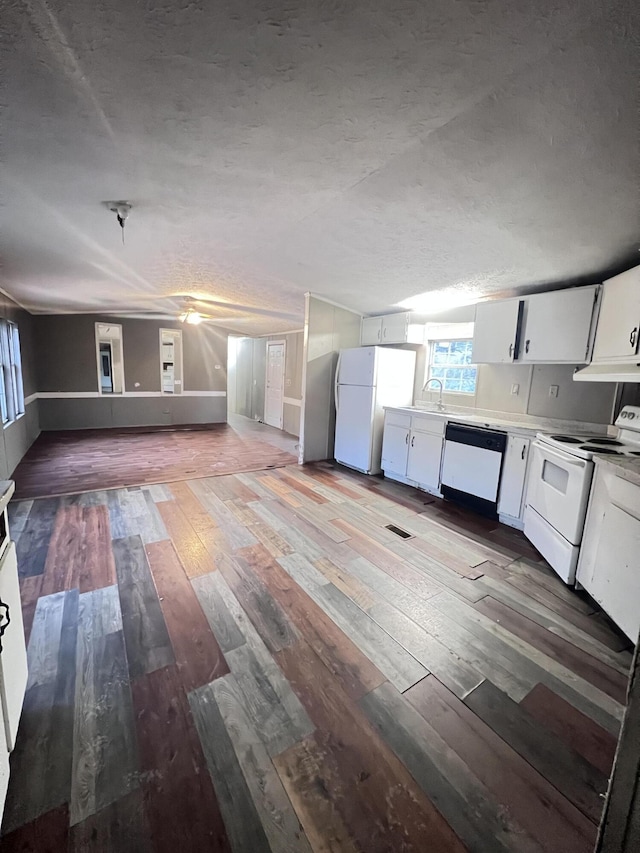 kitchen with a textured ceiling, hardwood / wood-style flooring, white appliances, a sink, and white cabinets