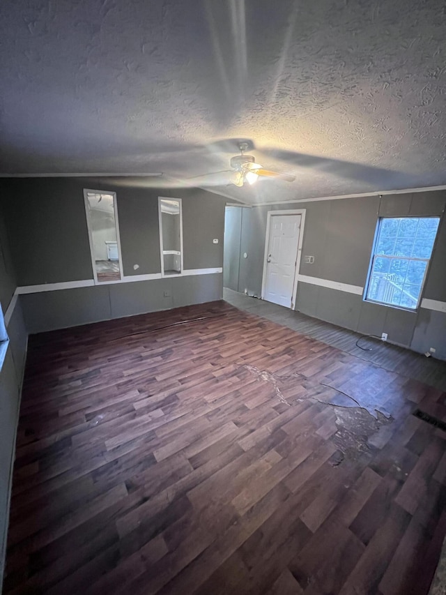 unfurnished living room with ceiling fan, a textured ceiling, ornamental molding, and wood finished floors