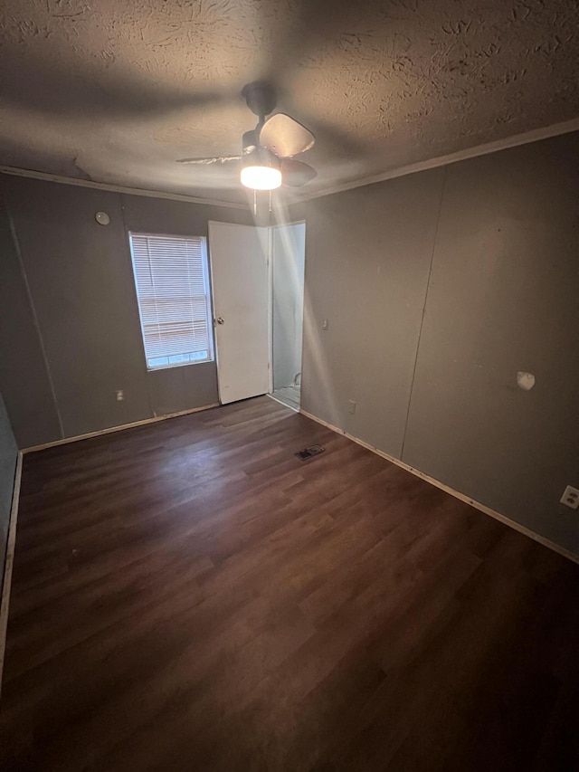 unfurnished room featuring dark wood-style floors, ornamental molding, a textured ceiling, and a ceiling fan