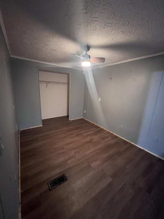 unfurnished bedroom featuring dark wood-style floors, visible vents, ornamental molding, and a textured ceiling