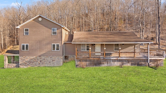 rear view of house with a yard, covered porch, and roof with shingles