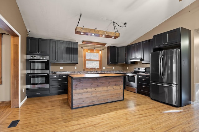 kitchen featuring visible vents, light wood-style flooring, stainless steel appliances, and vaulted ceiling