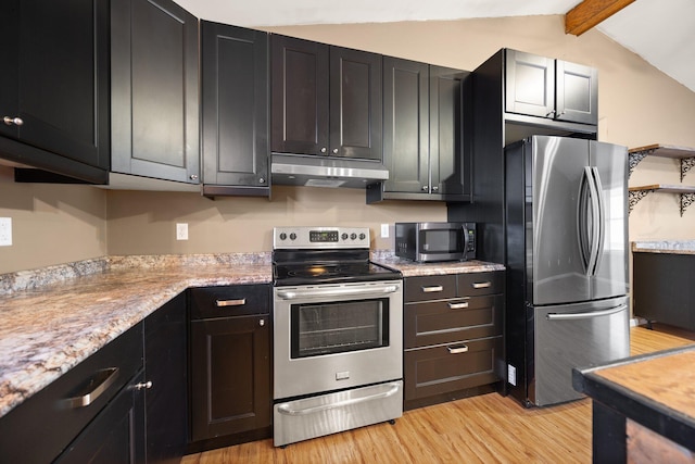 kitchen featuring light wood-style flooring, under cabinet range hood, appliances with stainless steel finishes, dark cabinets, and vaulted ceiling with beams