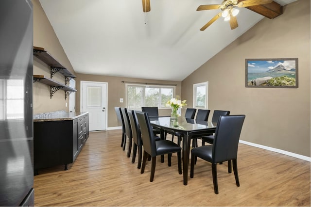 dining space with lofted ceiling with beams, a ceiling fan, baseboards, and light wood finished floors