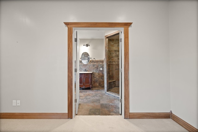 hallway featuring a sink, baseboards, and carpet floors