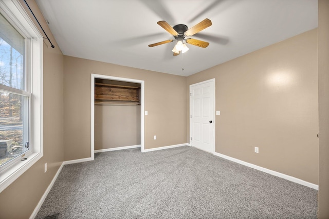 unfurnished bedroom with baseboards, multiple windows, and carpet floors