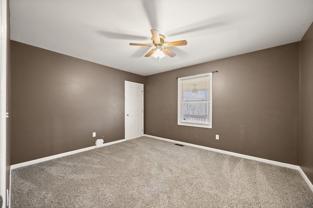 carpeted spare room with visible vents, baseboards, and a ceiling fan