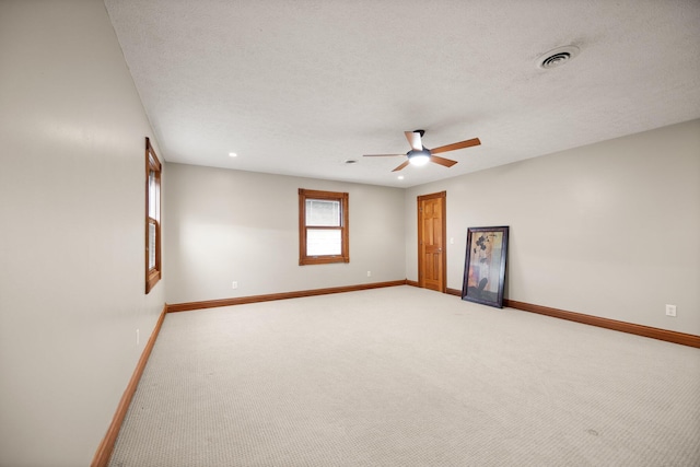 spare room with visible vents, baseboards, a textured ceiling, and a ceiling fan