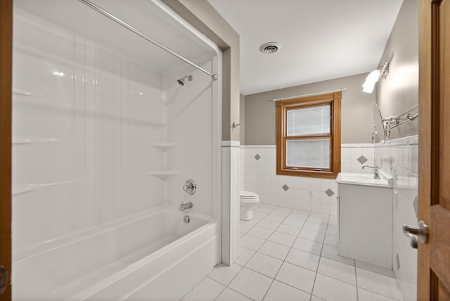 full bath with toilet, tile walls, tile patterned flooring, shower / bath combination, and vanity