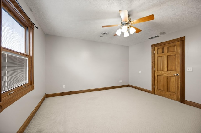 unfurnished room with a textured ceiling, light colored carpet, visible vents, and baseboards