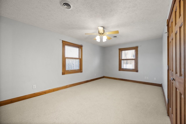 empty room with baseboards, visible vents, ceiling fan, a textured ceiling, and light carpet