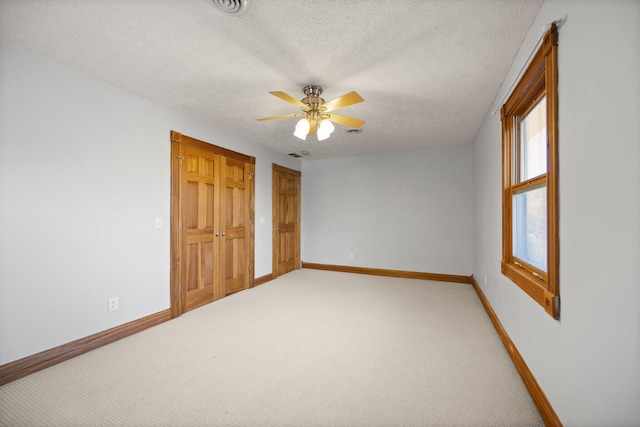 unfurnished bedroom featuring ceiling fan, light colored carpet, baseboards, and a textured ceiling