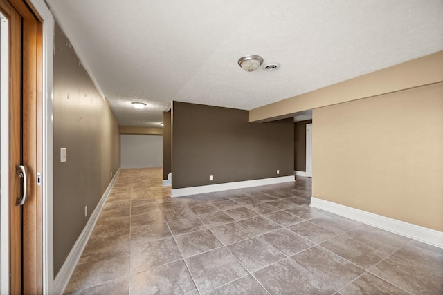 spare room featuring baseboards, visible vents, and a textured ceiling