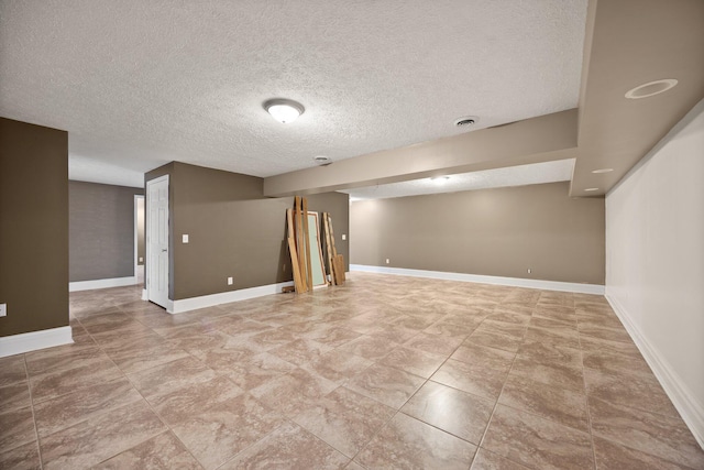 finished basement with visible vents, baseboards, and a textured ceiling