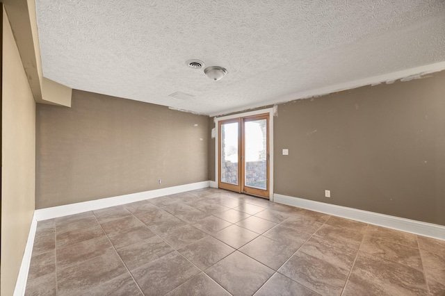 tiled empty room with visible vents, baseboards, and a textured ceiling