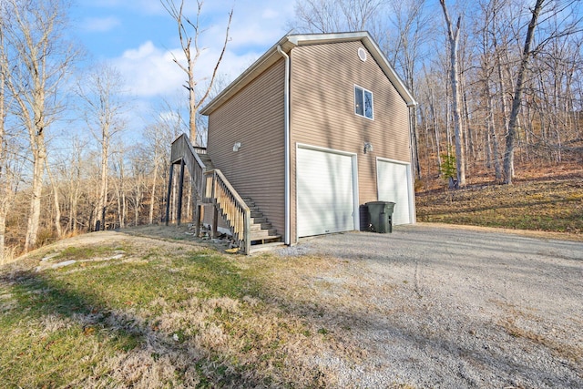 view of property exterior with stairs, an attached garage, and driveway