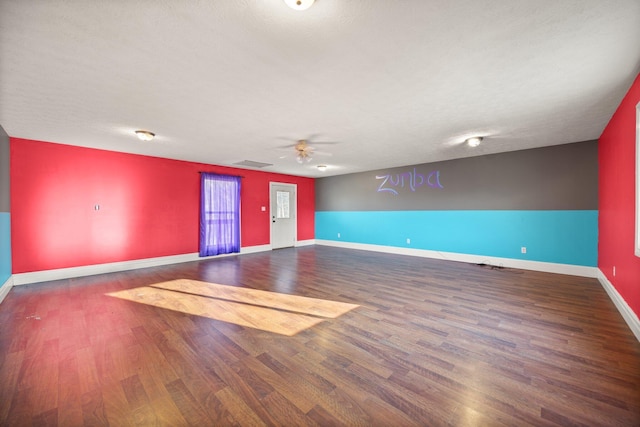 empty room featuring a ceiling fan, wood finished floors, baseboards, and a textured ceiling