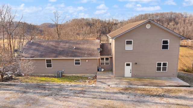 back of house with cooling unit and a chimney