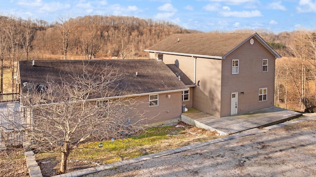 exterior space with a deck and a shingled roof