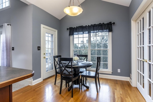 dining area featuring baseboards, vaulted ceiling, and wood finished floors