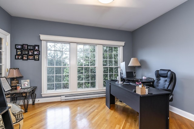 office with a baseboard heating unit, baseboards, and wood finished floors