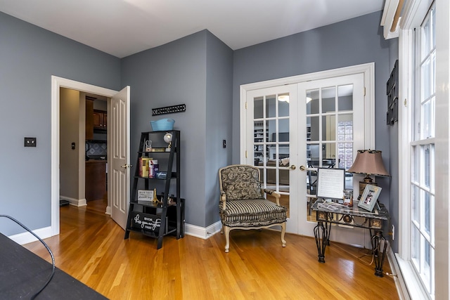 sitting room featuring french doors, plenty of natural light, wood finished floors, and baseboards