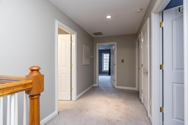 hallway featuring an upstairs landing, light colored carpet, visible vents, and baseboards