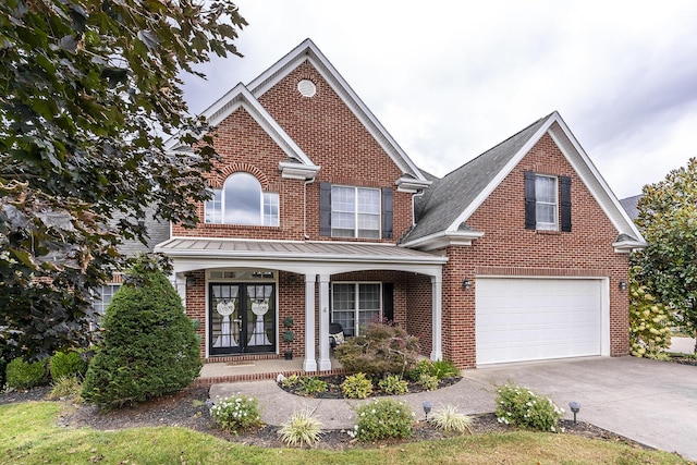 traditional-style home with french doors, a porch, concrete driveway, and brick siding