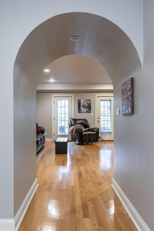 hallway with a wealth of natural light, light wood-style flooring, and baseboards