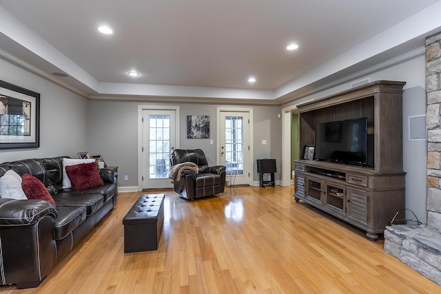 living room featuring recessed lighting, a raised ceiling, baseboards, and light wood finished floors