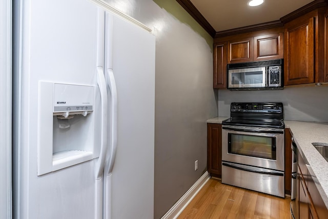 kitchen featuring stainless steel appliances, light stone counters, light wood-type flooring, and crown molding