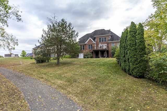 view of front of home with a deck, brick siding, and a front yard