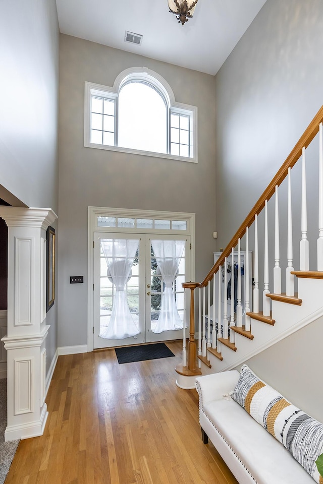 entrance foyer featuring a towering ceiling, stairs, visible vents, and wood finished floors