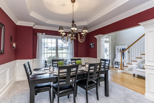 dining area featuring a healthy amount of sunlight, decorative columns, stairway, and a notable chandelier