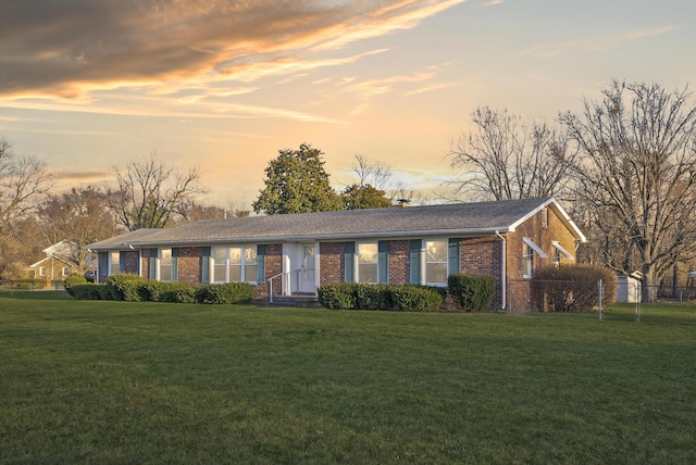 ranch-style home with brick siding, a lawn, and fence