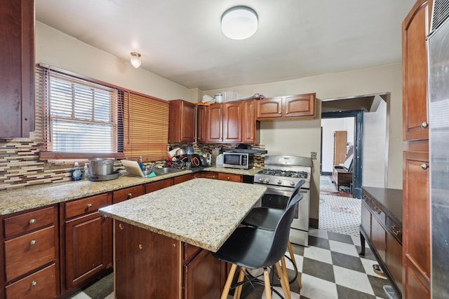 kitchen featuring dark floors, a center island, stainless steel appliances, decorative backsplash, and a sink