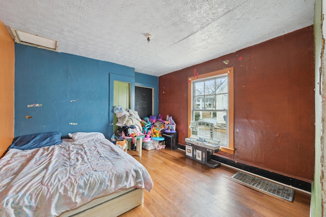 bedroom with visible vents, a textured ceiling, and wood finished floors