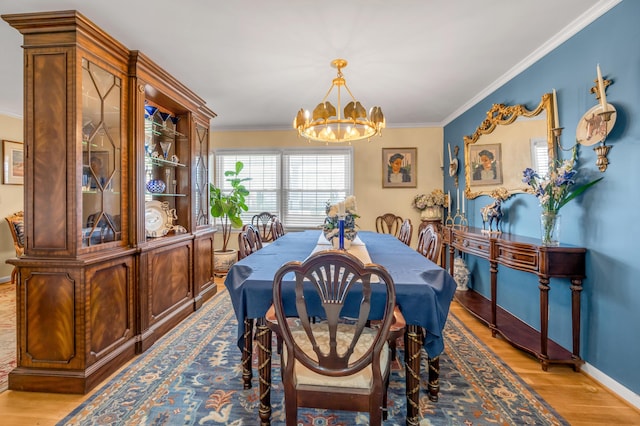 dining area featuring a chandelier, light wood finished floors, baseboards, and crown molding