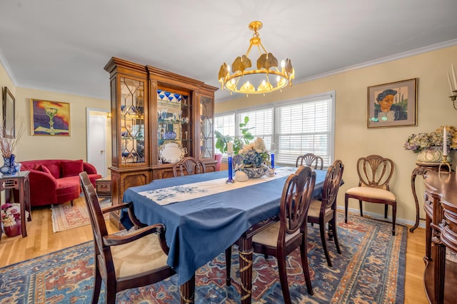 dining area featuring crown molding, a notable chandelier, baseboards, and wood finished floors