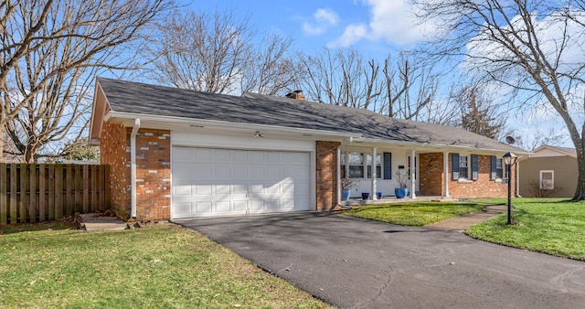 ranch-style home featuring a garage, brick siding, fence, driveway, and a front lawn