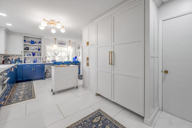 kitchen with marble finish floor, blue cabinetry, open shelves, light countertops, and white cabinets