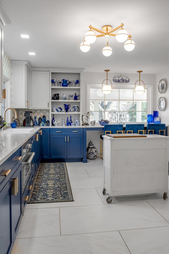 kitchen featuring tasteful backsplash, white cabinets, hanging light fixtures, blue cabinetry, and open shelves