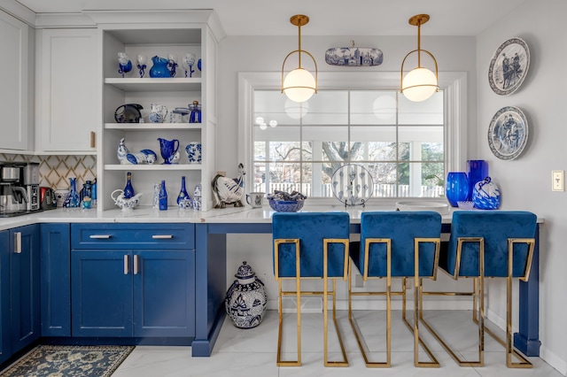 kitchen with blue cabinets, light countertops, backsplash, open shelves, and pendant lighting