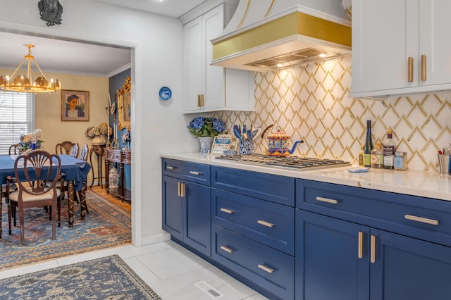 kitchen featuring custom range hood, stainless steel gas stovetop, decorative backsplash, white cabinetry, and blue cabinets