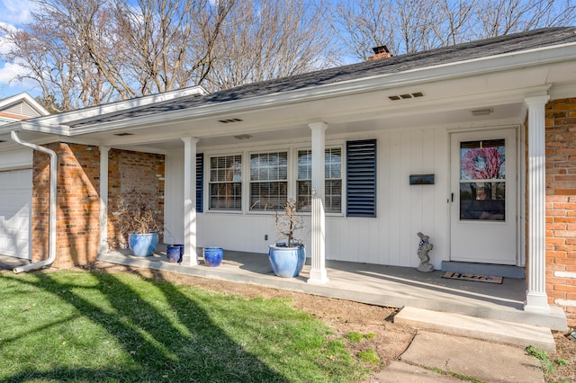 entrance to property with covered porch, brick siding, and a garage