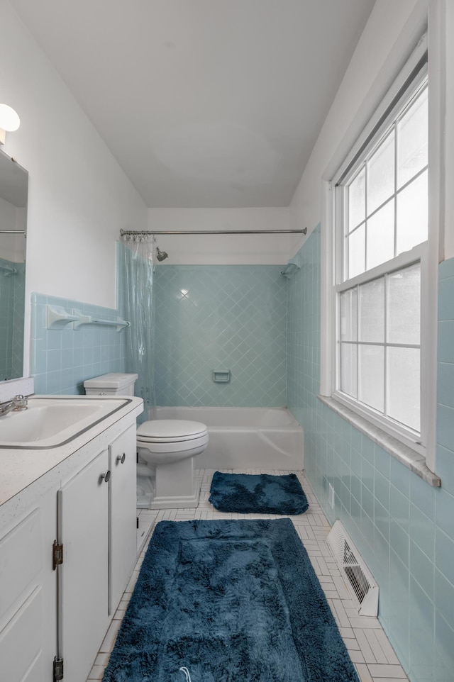 bathroom featuring shower / tub combo, visible vents, toilet, vanity, and tile walls