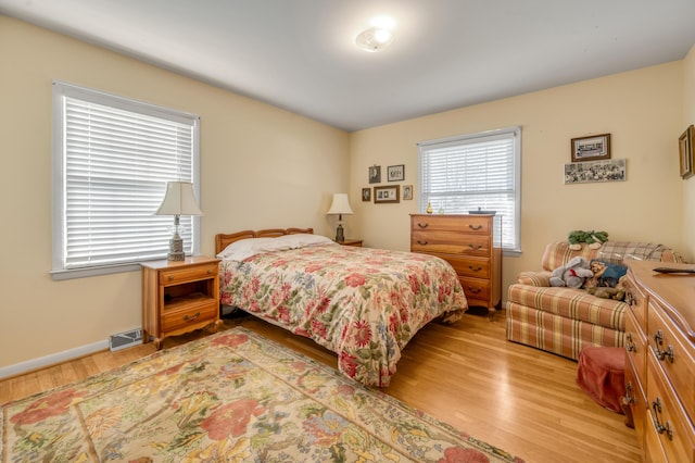 bedroom featuring light wood-style flooring, visible vents, and baseboards