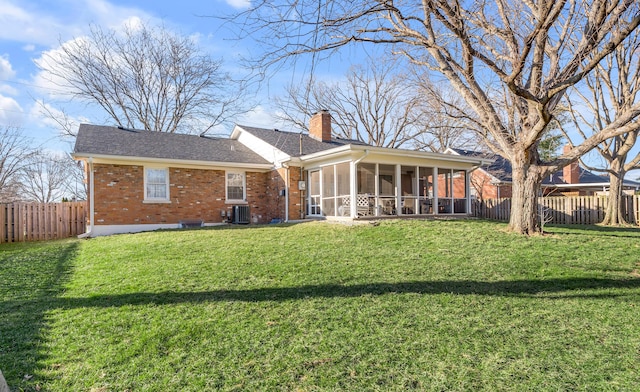 rear view of house with brick siding, a chimney, central air condition unit, a sunroom, and a fenced backyard