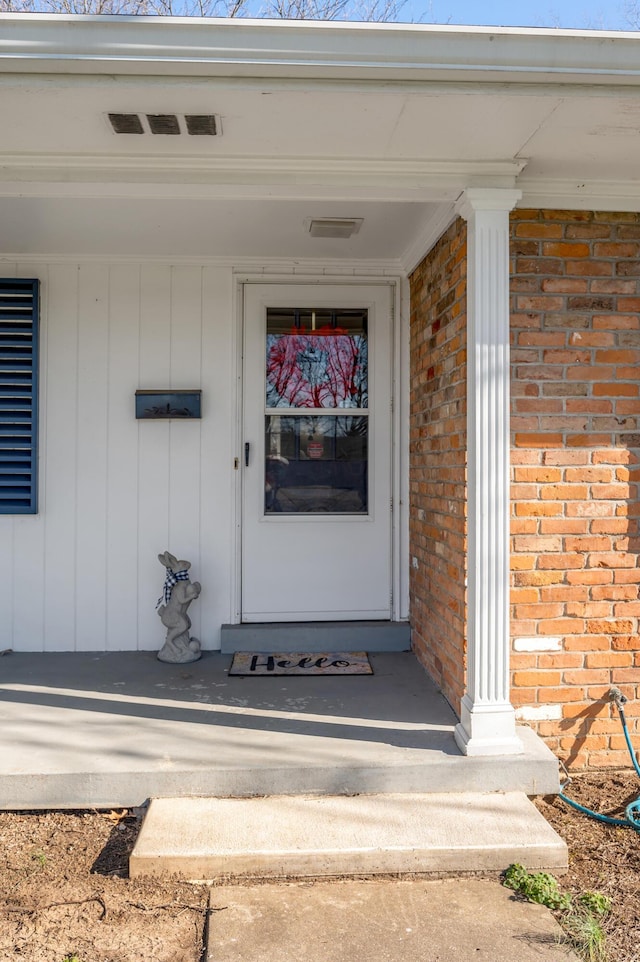 property entrance featuring visible vents and brick siding